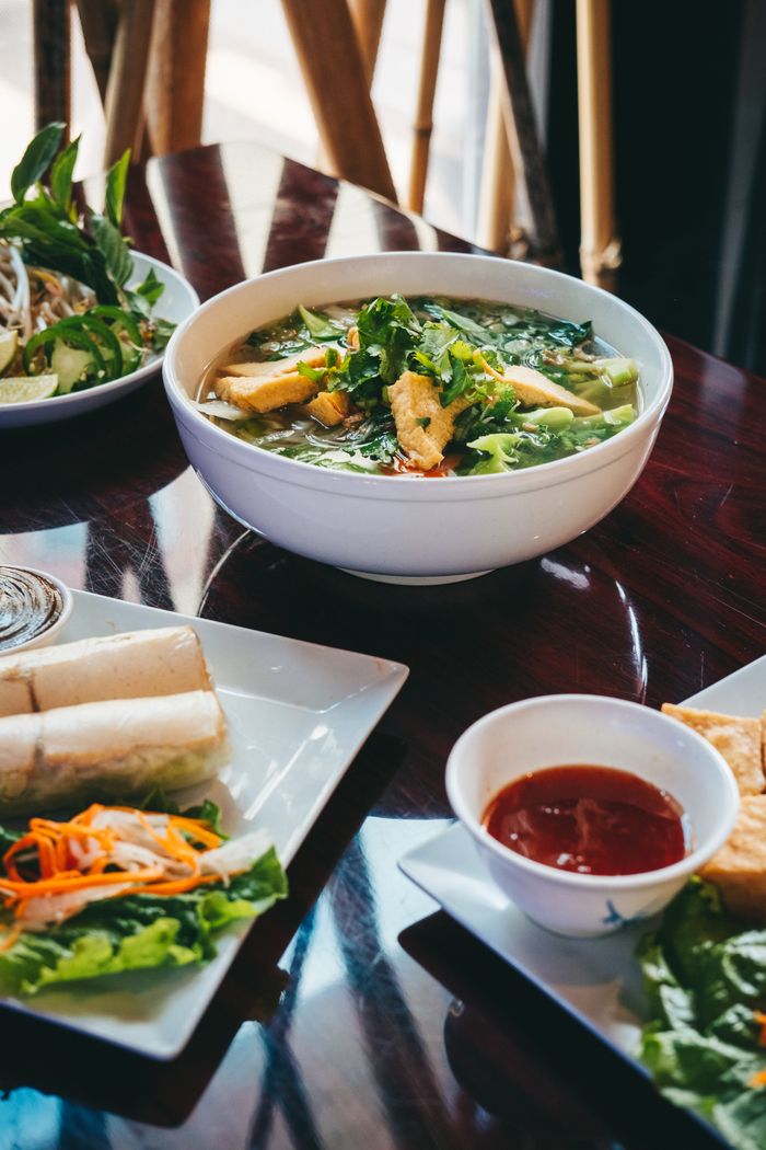 Delicious bowl of Vietnamese pho with fresh herbs and vegetables, captured on a wooden table.