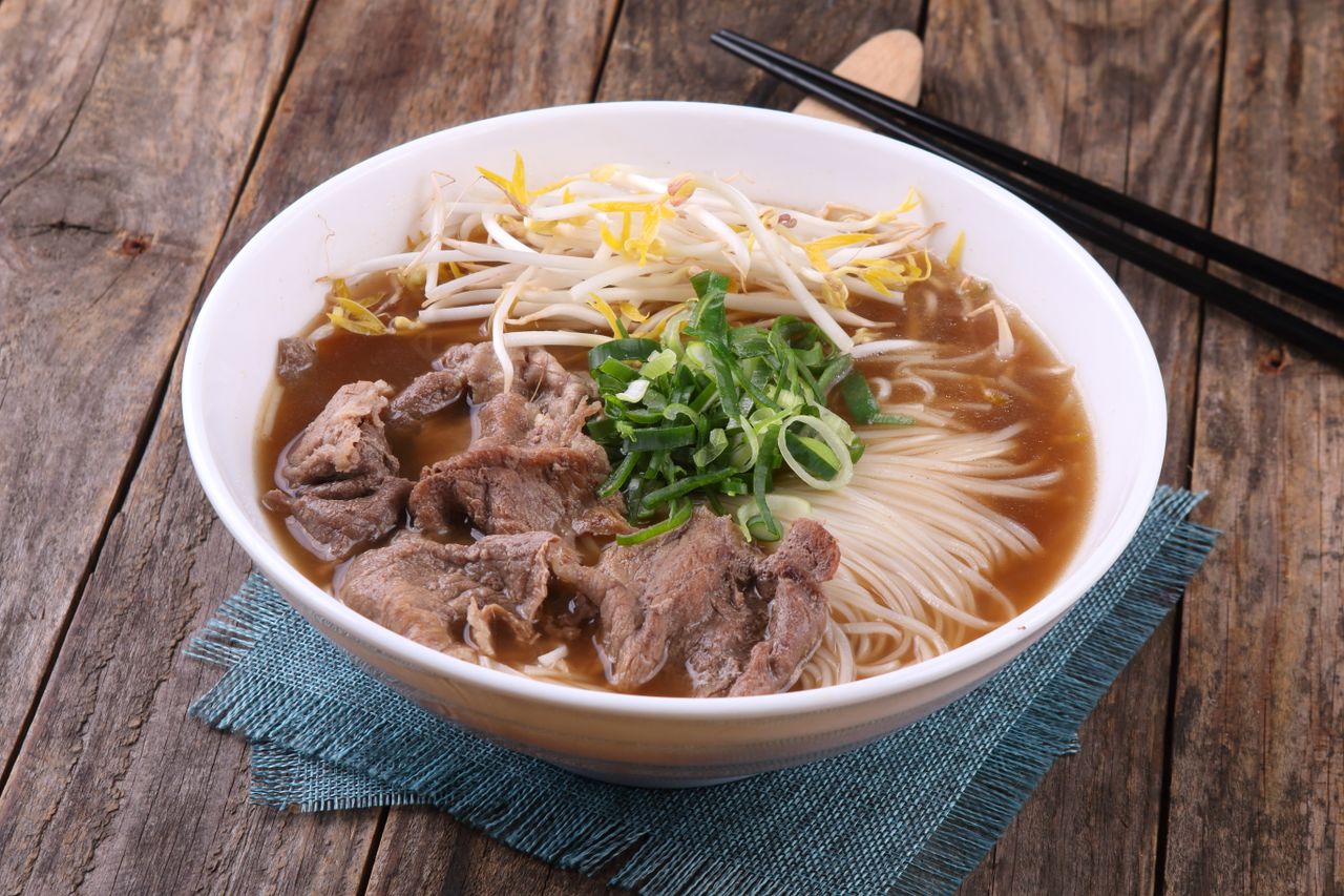 A savory bowl of Vietnamese pho with beef, noodles, and fresh greens.